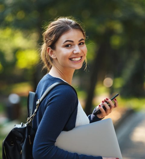 Smiling young teenage girl carrying backpack walking