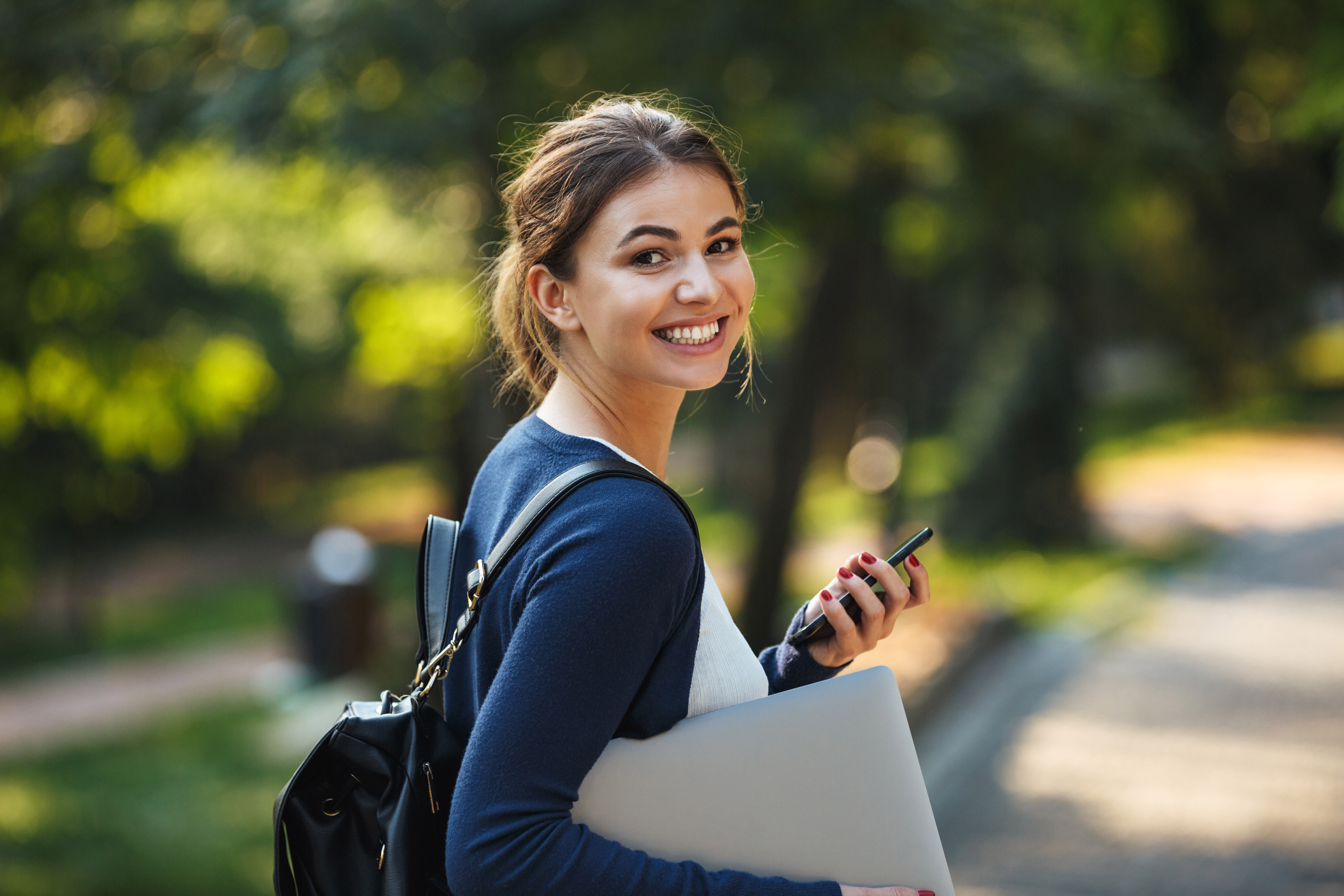 Smiling young teenage girl carrying backpack walking