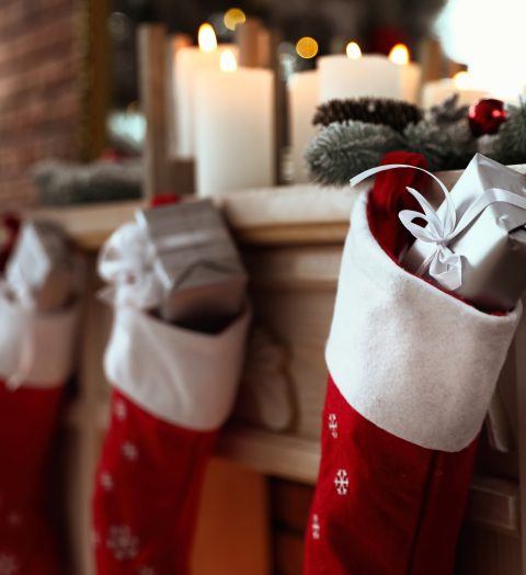 Decorative fireplace with Christmas stocking and gifts in stylish room interior